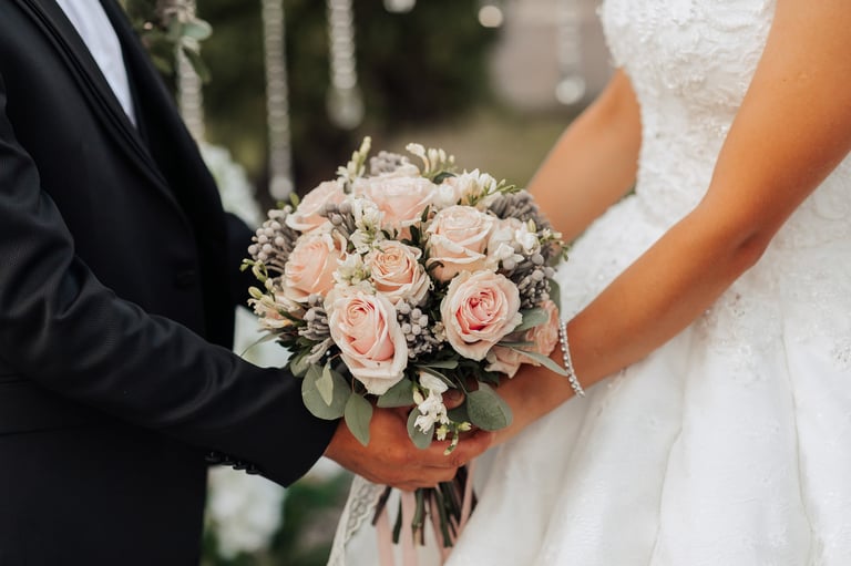 A man and woman holding a bouquet of flowers, bride and groom on wedding day