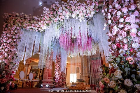 Lavish wedding entrance decorated with cascading white and pink flowers and hanging floral installations creating a luxurious backdrop