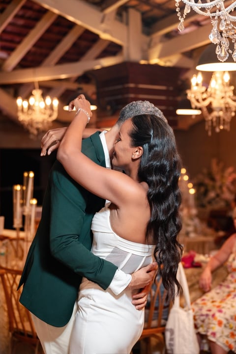 Bride and groom dancing at wedding reception in elegant ballroom with chandeliers and gold decorations
