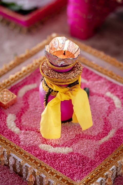 Diamond engagement ring with yellow ribbon bow displayed on ornate pink and gold fabric cushion