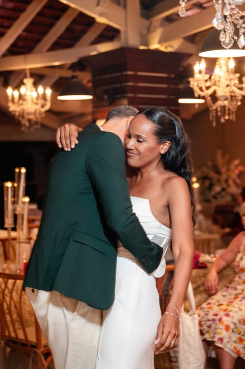 Couple embracing at elegant indoor event with chandeliers and gold decor in background