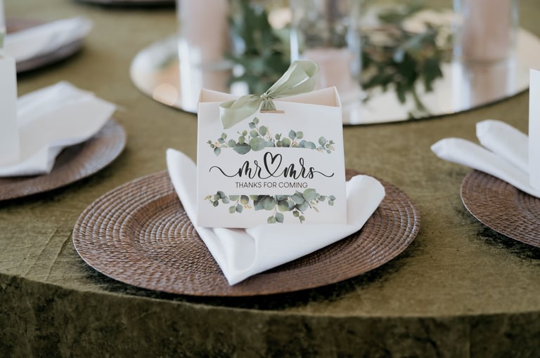 Wedding table setting with Mr and Mrs place card tied with ribbon on woven charger plate with white napkin