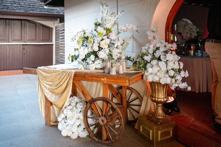 Decorated wooden table with large cart wheels and white floral arrangements at an elegant event venue