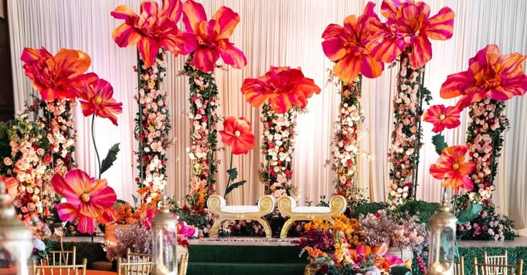 Elegant floral event backdrop featuring tall arrangements of hot pink flowers and white blooms on black stems with white curtain background