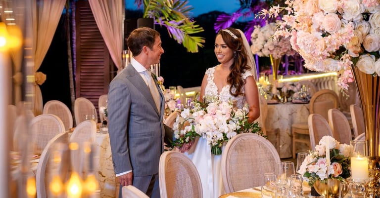 Bride and groom at elegant wedding reception with white floral arrangements and candlelit tables