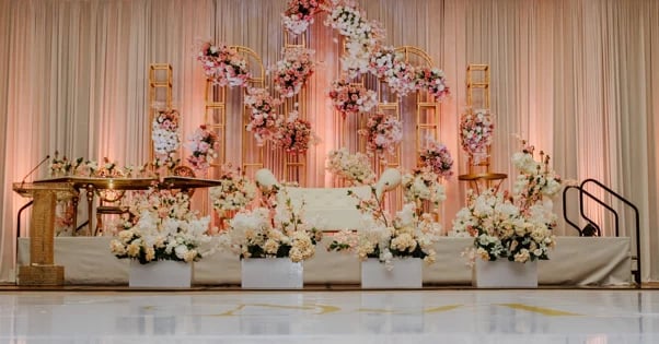 Elegant wedding stage backdrop with hanging floral arrangements in rose and white tones above white planters with flowers
