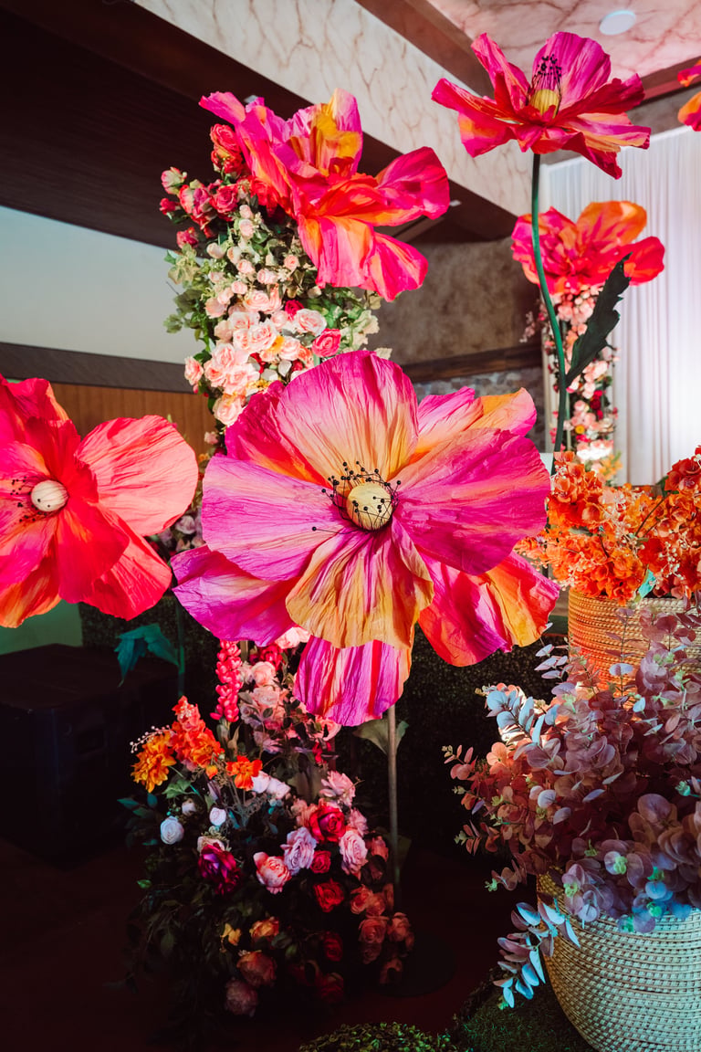 Large vibrant pink and yellow dahlias with smaller flowers in an elaborate floral display installation