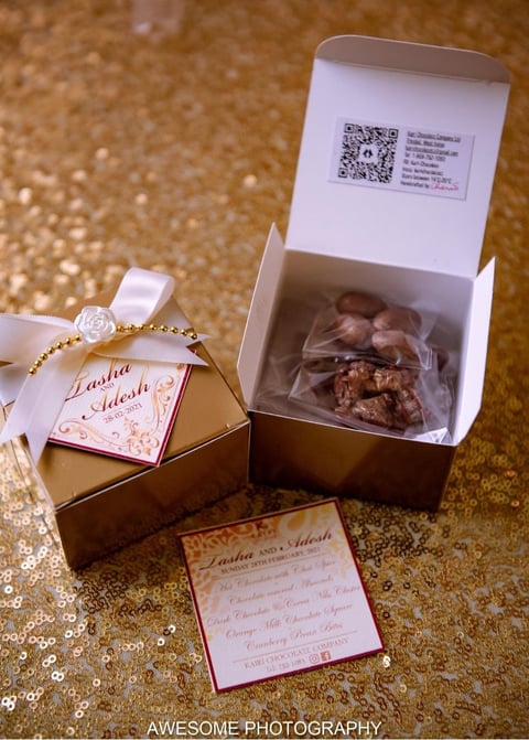 Luxury gift boxes containing chocolates and branded packaging displayed on a gold sequined background with product cards.