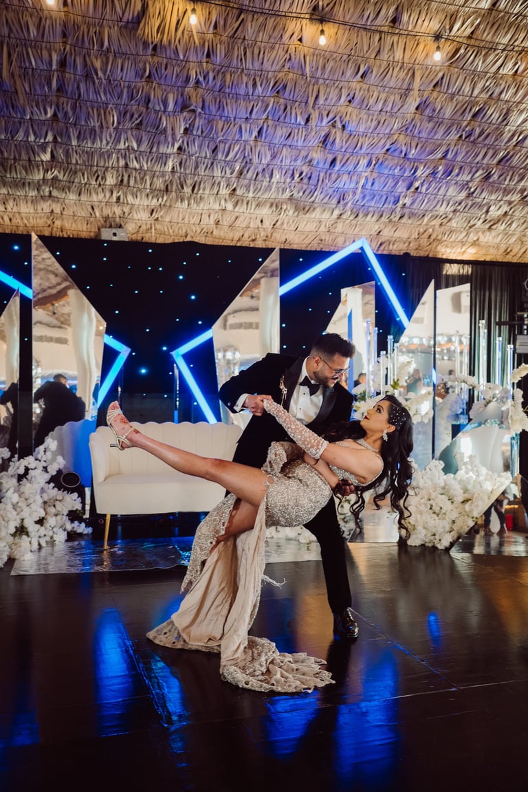 Bride and groom performing first dance at wedding reception with blue neon star decorations and white floral arrangements